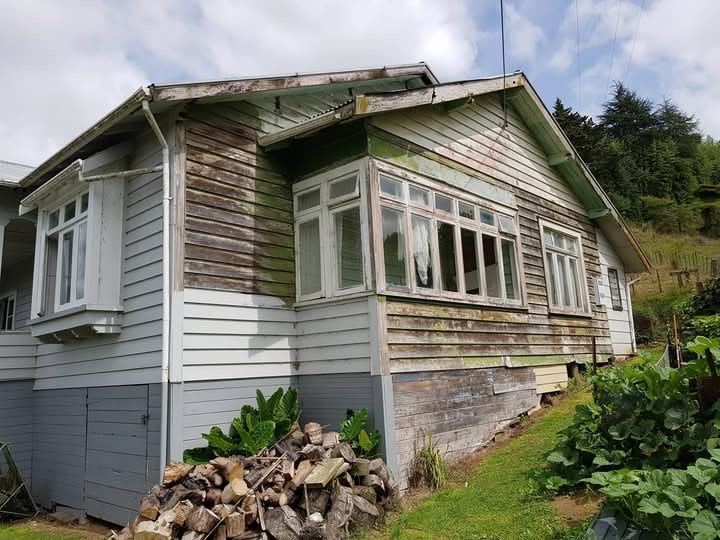 A weatherboard house with weathered paint before the job started