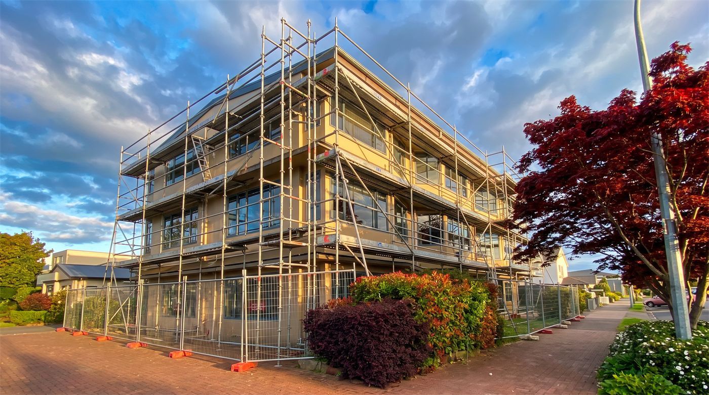 A three-storey commercial building fully scaffolded on every elevation at golden hour