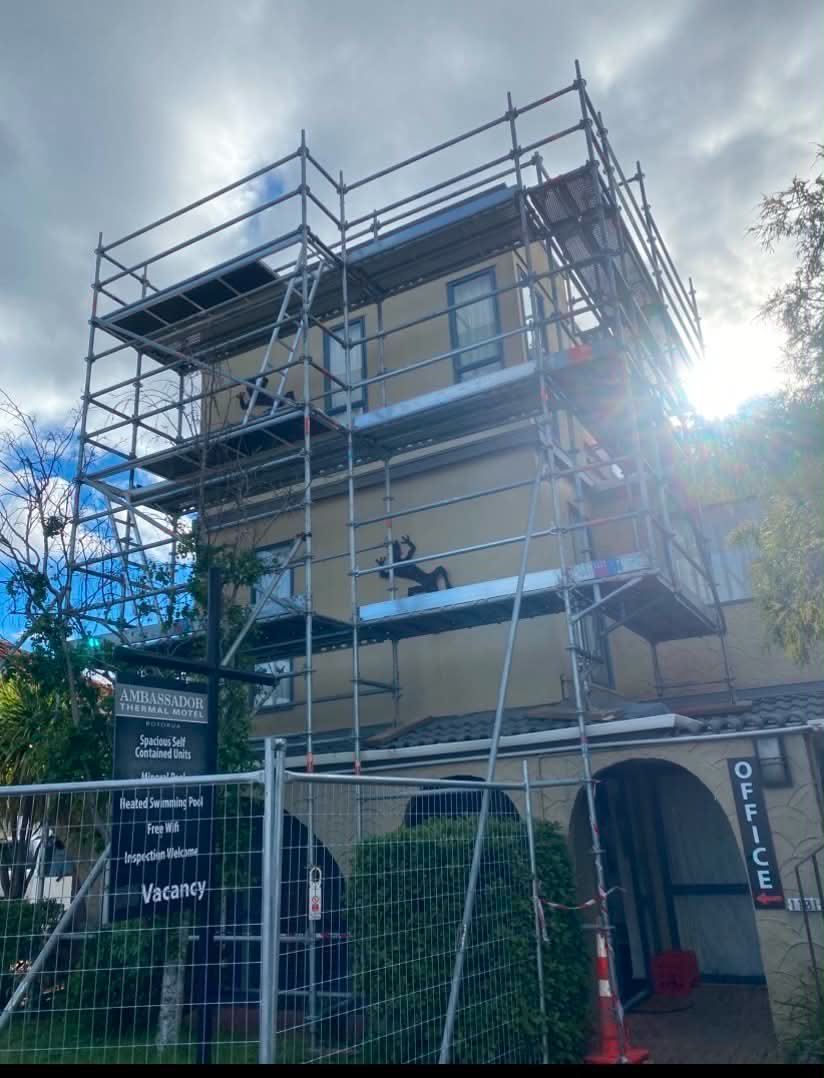 A tall multi-level scaffold tower erected up the side of a motel building