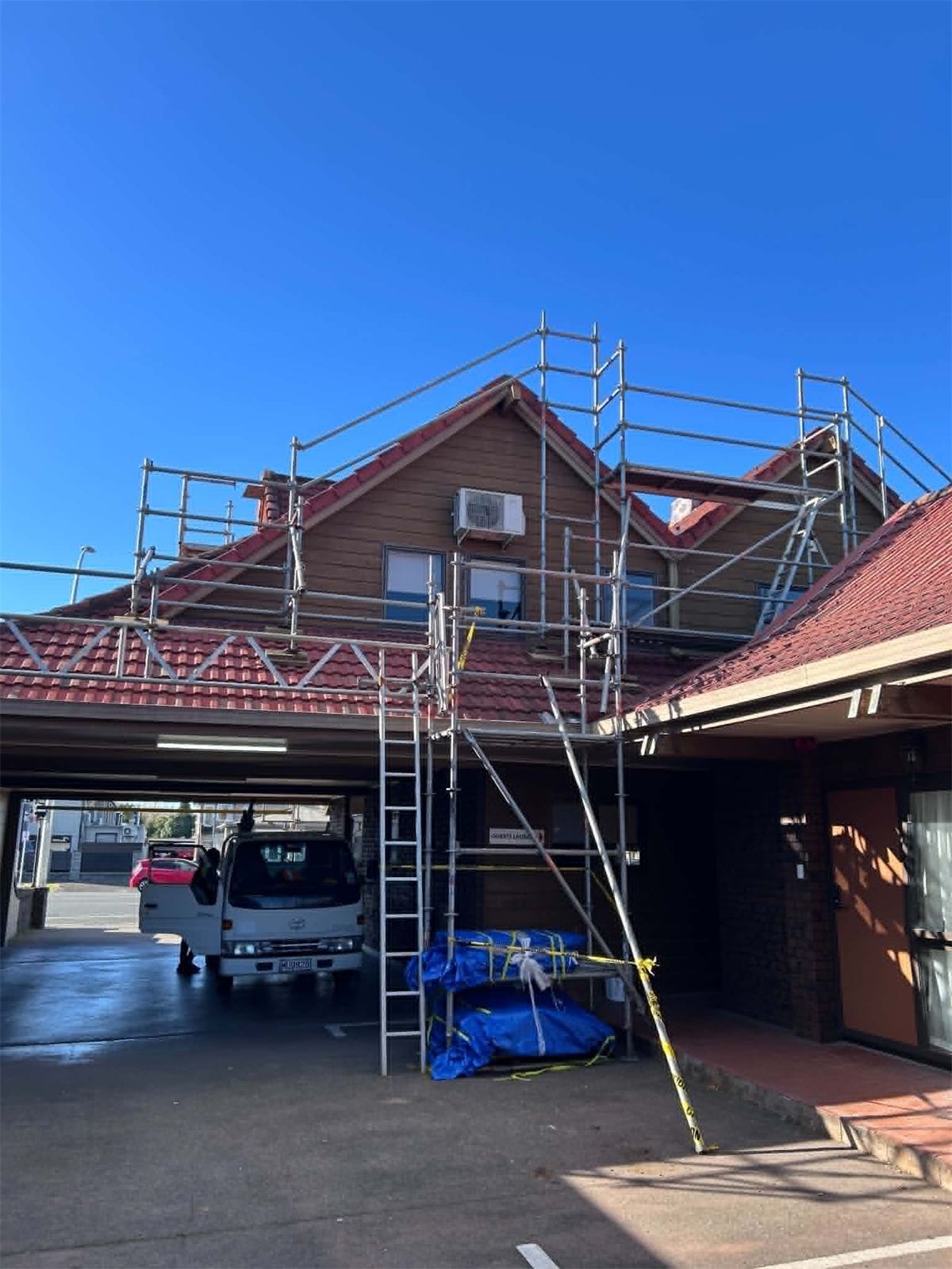 Scaffolding and edge protection erected around the gable end and roofline of a two-storey building